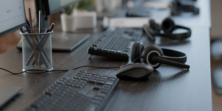 Audio headset used by call center agents to help clients Audio headset used by call center agents to help clients and do telecommunication with technology. Empty customer service workstation with headphones, computers and modern gadgets.